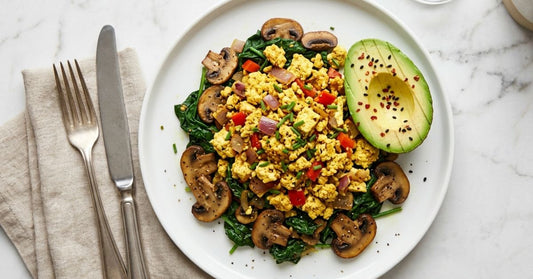 Tofu scramble over sautéed spinach and mushrooms, with half an avocado on the side served